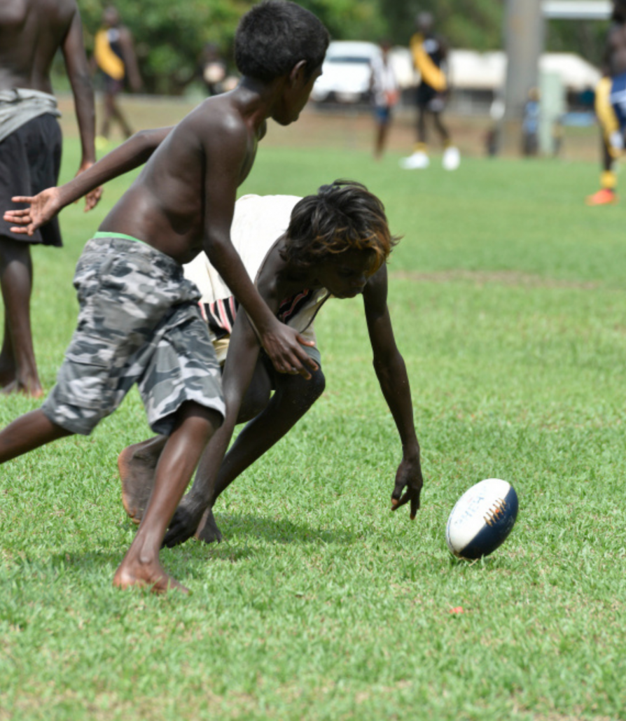 kids playing footy on field in community